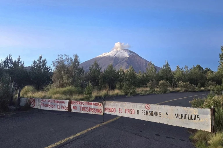 aviso no pasar sobre la carretera y atrás el volcan popocatepetl