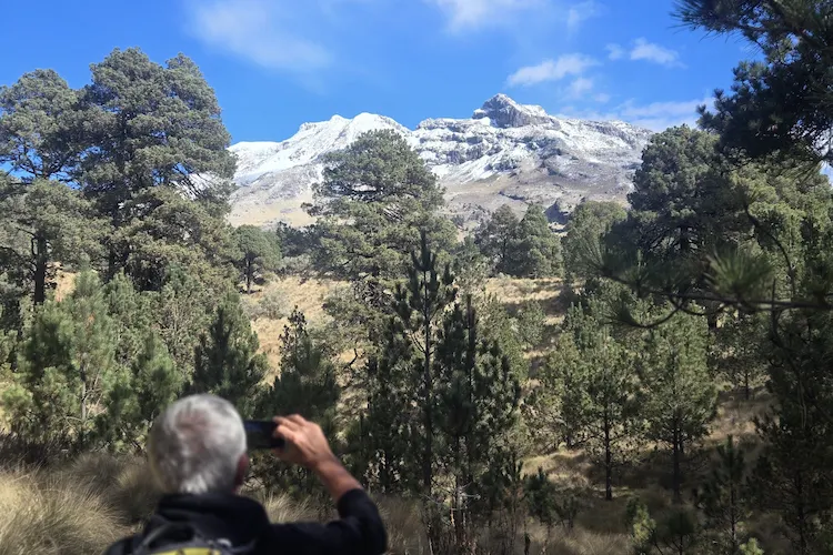 Turista fotografiando el volcán Iztaccíhuatl desde el bosque