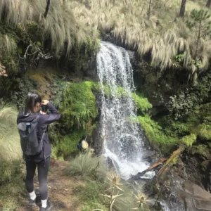 Turista tomando fotos de una cascada en el Parque Nacional Izta-Popo